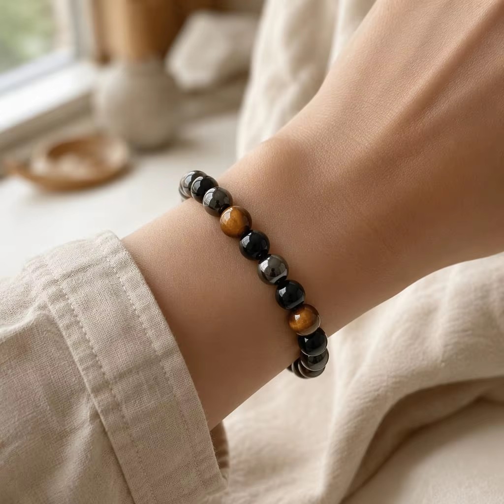The Triple Shield bracelet worn on a wrist with a light linen sleeve